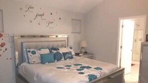 A bedroom with a bed, a nightstand, a lamp, and a wall with decorative text. -  One minute walk to the Beach -Norfolk (Norfolk)
