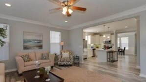 A spacious living room with a ceiling fan, a sofa, a coffee table, and a view into the kitchen. -  One minute walk to the Beach -Norfolk (Norfolk)
