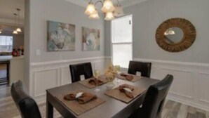 A dining area with a rectangular table, four chairs, and a chandelier. -  One minute walk to the Beach -Norfolk (Norfolk)