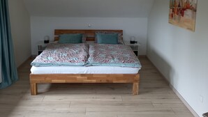 A bedroom with a wooden bed, a ceiling light, and a painting on the wall. - Very nice apartment with garden, perfect starting point for hikes, bike tours etc.   (Hürtgenwald)