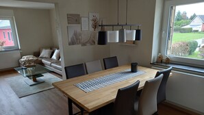 A modern dining area with a wooden table, black chairs, and a glass coffee table. - Very nice apartment with garden, perfect starting point for hikes, bike tours etc.   (Hürtgenwald)