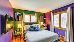 Een slaapkamer met een bed, nachtkastjes, een spiegel en een raam met gordijnen.