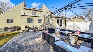 Een huis met een patio, inclusief tuinmeubilair, een vuurkorf en een overdekte zithoek.