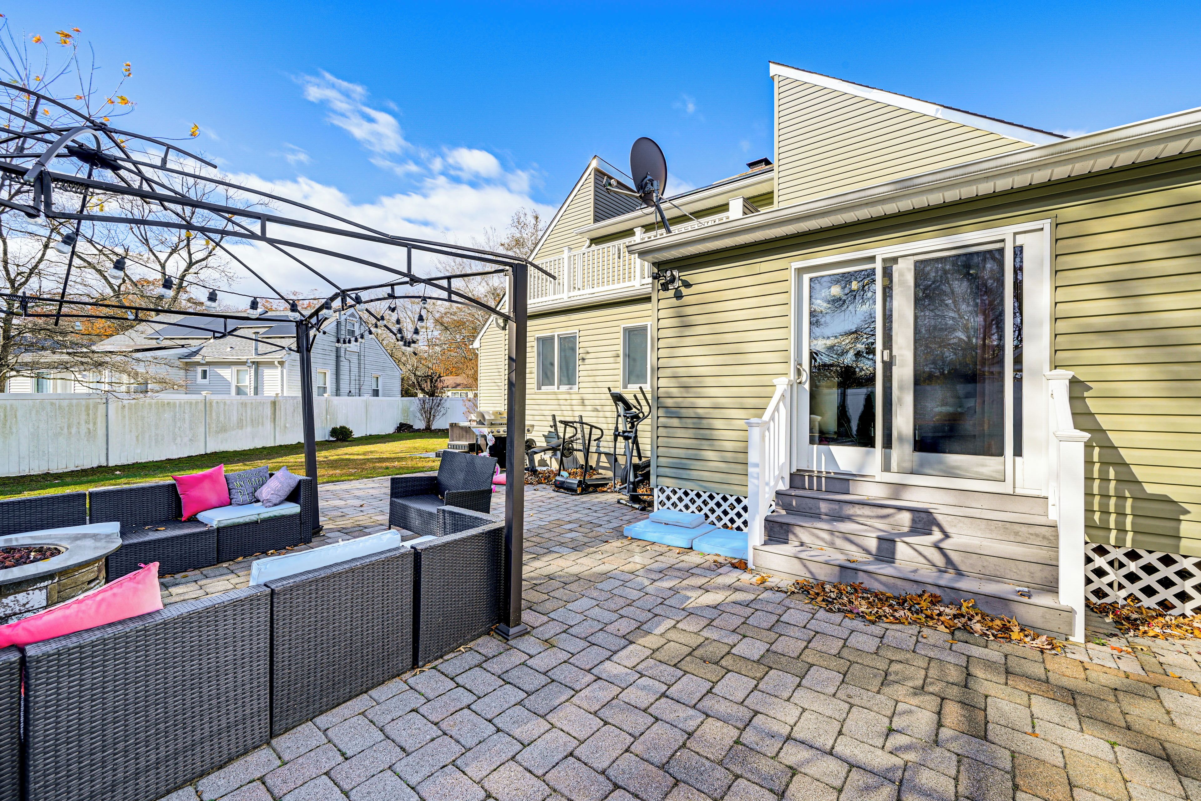 A patio with outdoor furniture, a fire pit, and a satellite dish on a house.