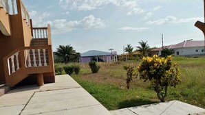 A residential area with a house featuring a balcony and a small garden. - Vacation Home On Caribbean Coast For Rent with Private Beach in Honduras (Balfate Colon)