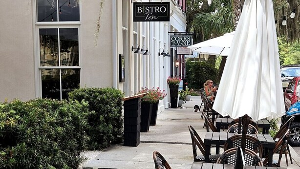 An outdoor cafe area with tables and chairs, a white umbrella, and a sign for 'Bistro Ten'. - Low Country Cottage in Beautiful Habersham (Beaufort)