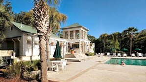 A two-story building with a covered porch, a swimming pool, and outdoor seating. - Low Country Cottage in Beautiful Habersham (Beaufort)