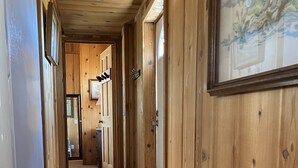 A wooden hallway with a patterned rug, wooden walls, and a ceiling with recessed lighting.