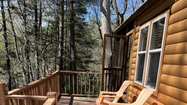 A wooden deck with two Adirondack chairs and a wooden railing.