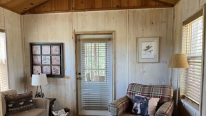A cozy room with a plaid sofa, a small table, a lamp, and a framed picture on the wall.