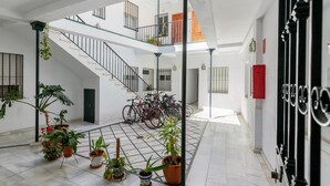 Tilava sisätila, jossa on laattalattia, useita ruukkukasveja, polkupyöriä ja portaikko, joka johtaa ylemmälle tasolle.