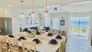 Een eetruimte met een grote tafel, houten stoelen en hangende lampen.