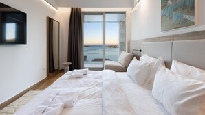 Ein Hotelzimmer mit einem großen Bett, einem Flachbildfernseher, einem Gemälde und Blick aufs Meer.