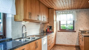 A kitchen with wooden cabinets, a stainless steel sink, and a window with a view of greenery.