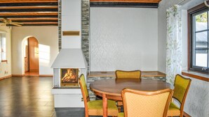 A dining area with a central table, chairs, and a built-in fireplace.