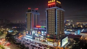A hotel with two prominent towers, each with illuminated signage and multiple floors. - Green Island Holiday Hotel (Jiangmen)
