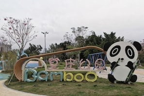 A playground with a large panda sculpture, a swing set, and a slide.