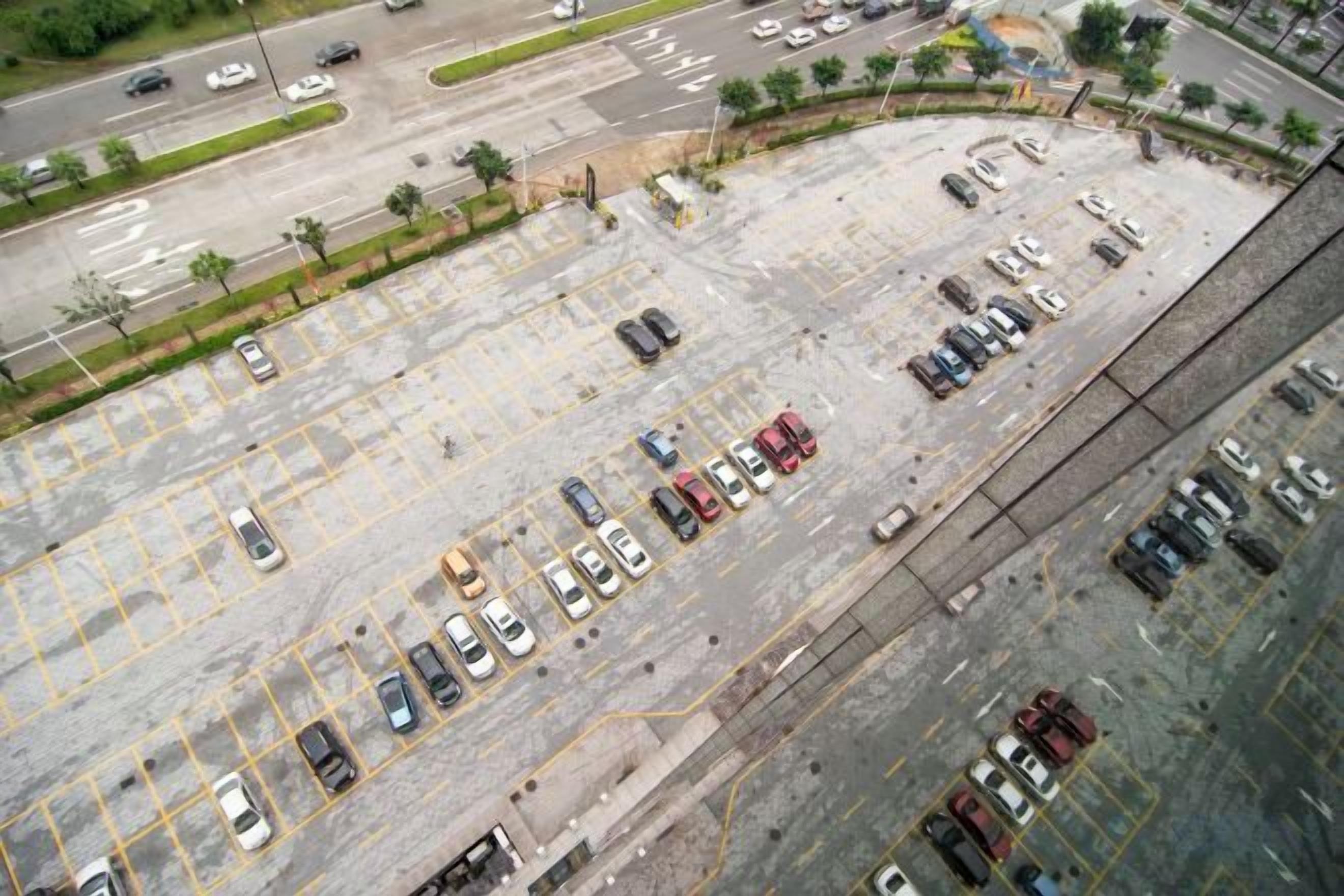 An aerial view of a parking lot with multiple rows of parked cars.