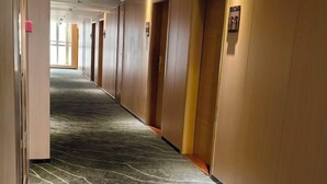 A hotel hallway with a carpeted floor and wooden walls. - Green Island Holiday Hotel (Jiangmen)