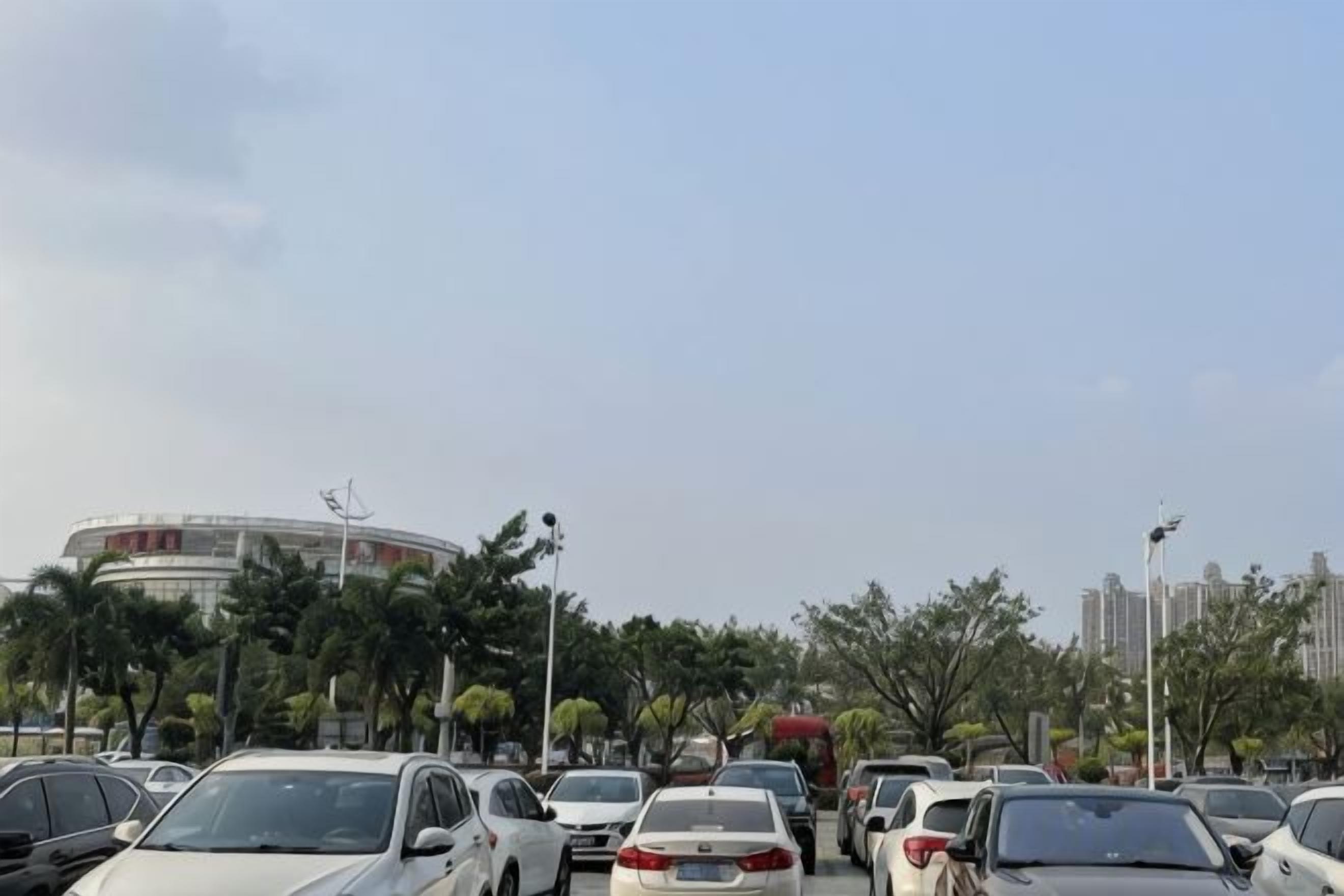 A parking lot with multiple cars and a building in the background.