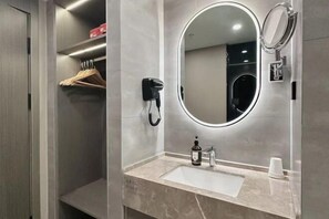 Ein Badezimmer mit Waschtisch, Spiegel, Haartrockner und Handtuchhalter.