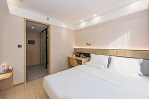 Ein Hotelzimmer mit Bett, Nachttisch und einem kleinen Schreibtisch mit Stuhl.