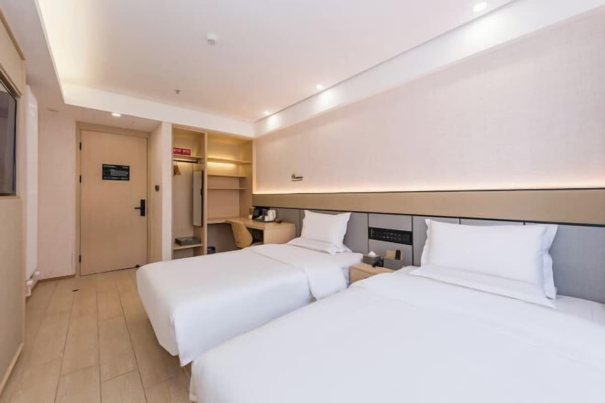 A hotel room with two beds, a desk, and a wardrobe.