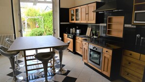 Una cocina con piso a cuadros, armarios de madera, una estufa de acero inoxidable y una zona de comedor con taburetes de bar.