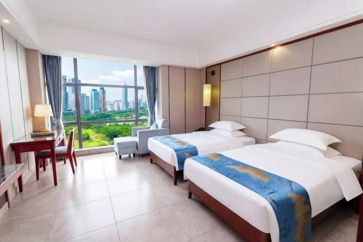 A hotel room with two beds, a desk, and a chair.