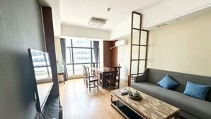 A living room with a sofa, coffee table, TV, and dining area. - Yihao Hotel (Qionghai)