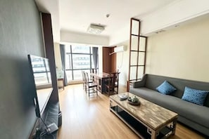 A living room with a sofa, coffee table, TV, and dining area.