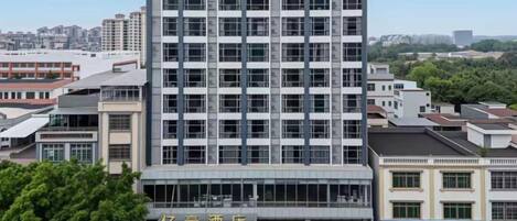 A multi-story hotel with a modern facade, a parking lot, and a sign indicating the hotel name.