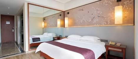 Une chambre d’hôtel avec un grand lit, une table de chevet avec un téléphone, un miroir et un luminaire fixé au mur.