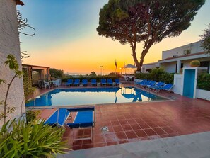 A pool area with lounge chairs and a view of the sunset. - Villa Mena (Forio)