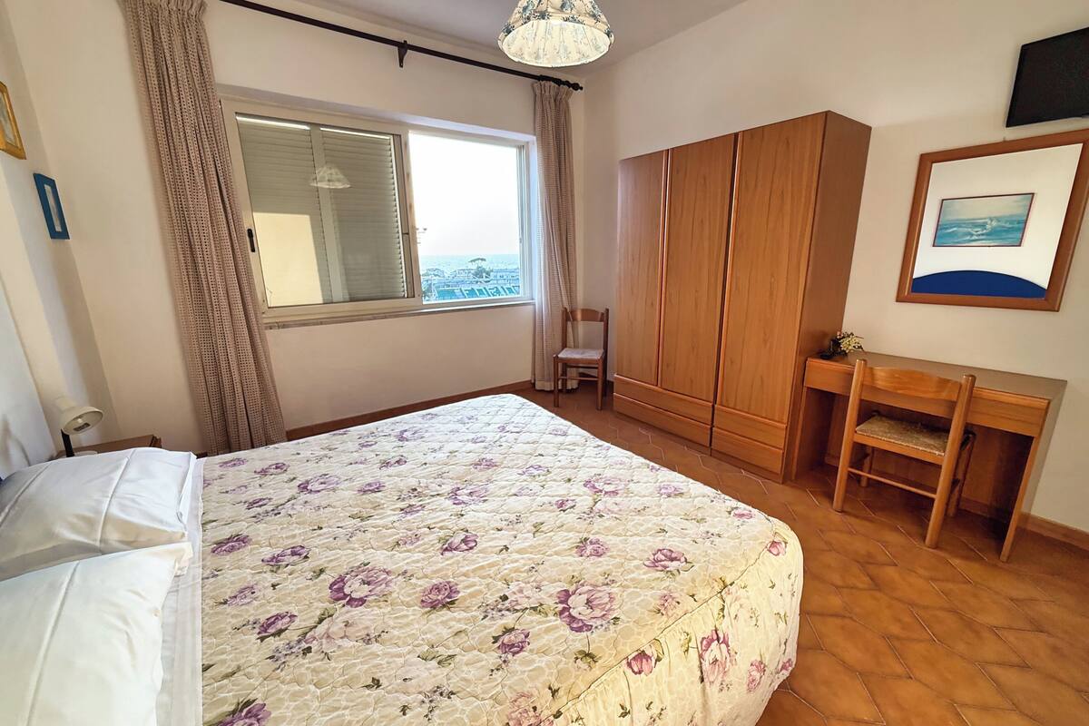 Un dormitorio con una cama grande, un armario de madera, un escritorio y una silla.