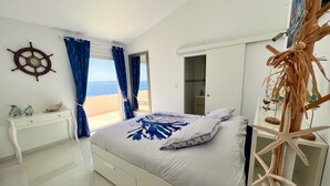 A bedroom with a bed, a desk, a wardrobe, and a view of the sea. - Maison Paradisiaque A Rosas A Proximite DES Plages (CANYELLES ALMADRABA (AJUNTAMENT ROSES))
