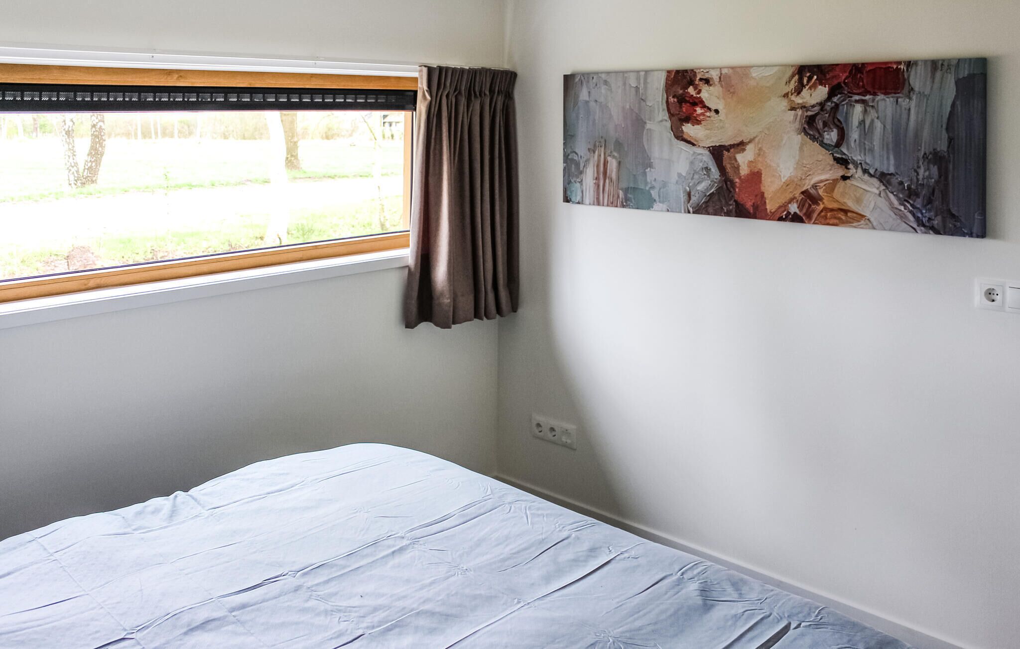 Una camera da letto con un letto, una finestra con tende e un quadro appeso al muro.
