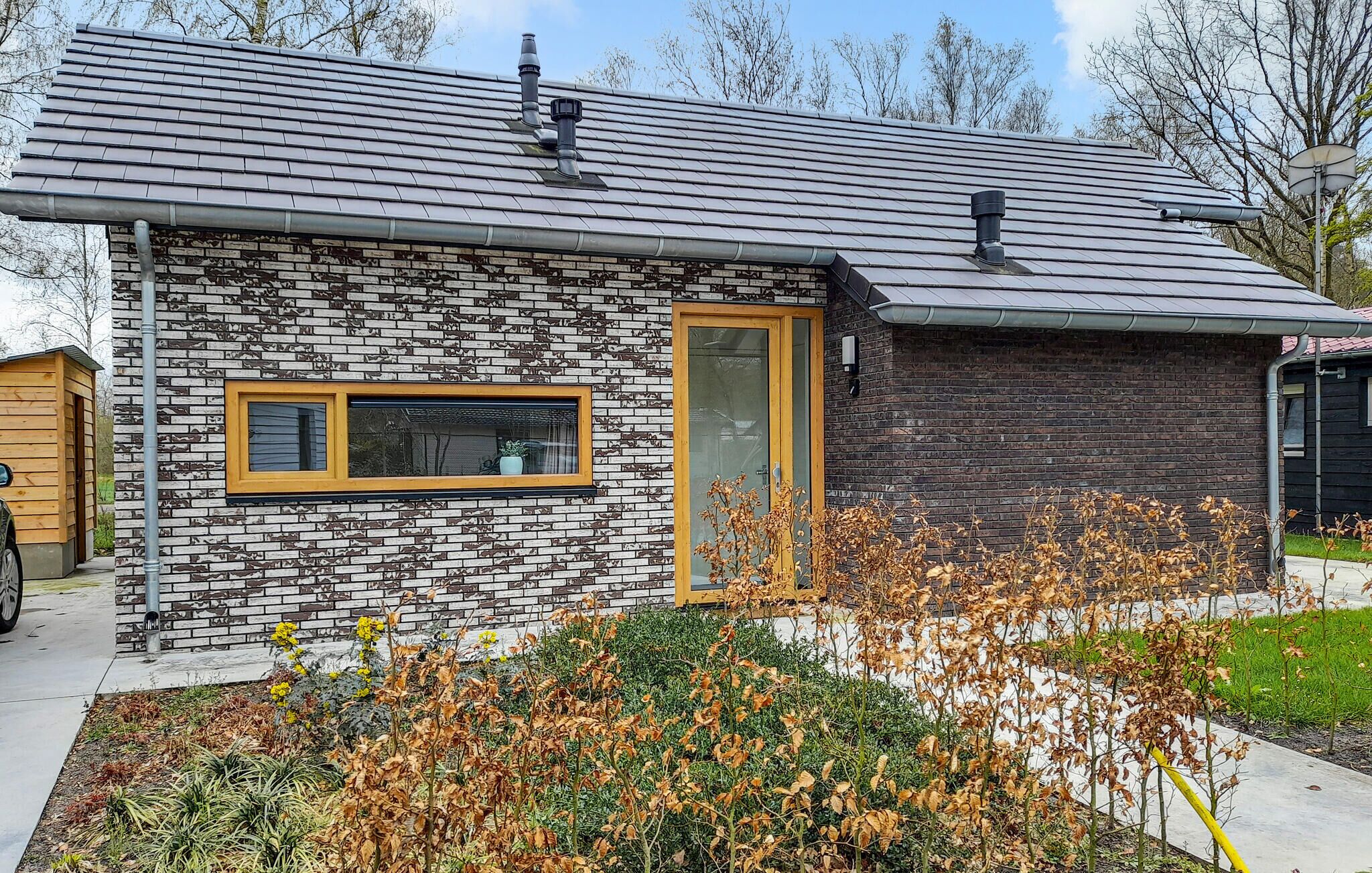 Une maison moderne avec une façade en pierre, une porte en bois et une fenêtre.