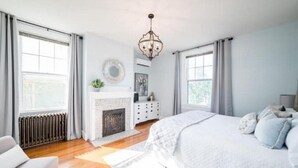 Ein Schlafzimmer mit einem großen Bett, einem Kamin und einer Chandelier.