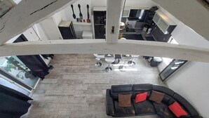 A spacious living area with a black leather sofa, a dining table with four chairs, and a kitchen area in the background. - Gorgeous home in Villars (Villars)