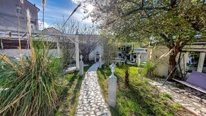 A garden pathway with a stone-tiled walkway, surrounded by greenery and a white fence. - Gorgeous home in Villars (Villars)