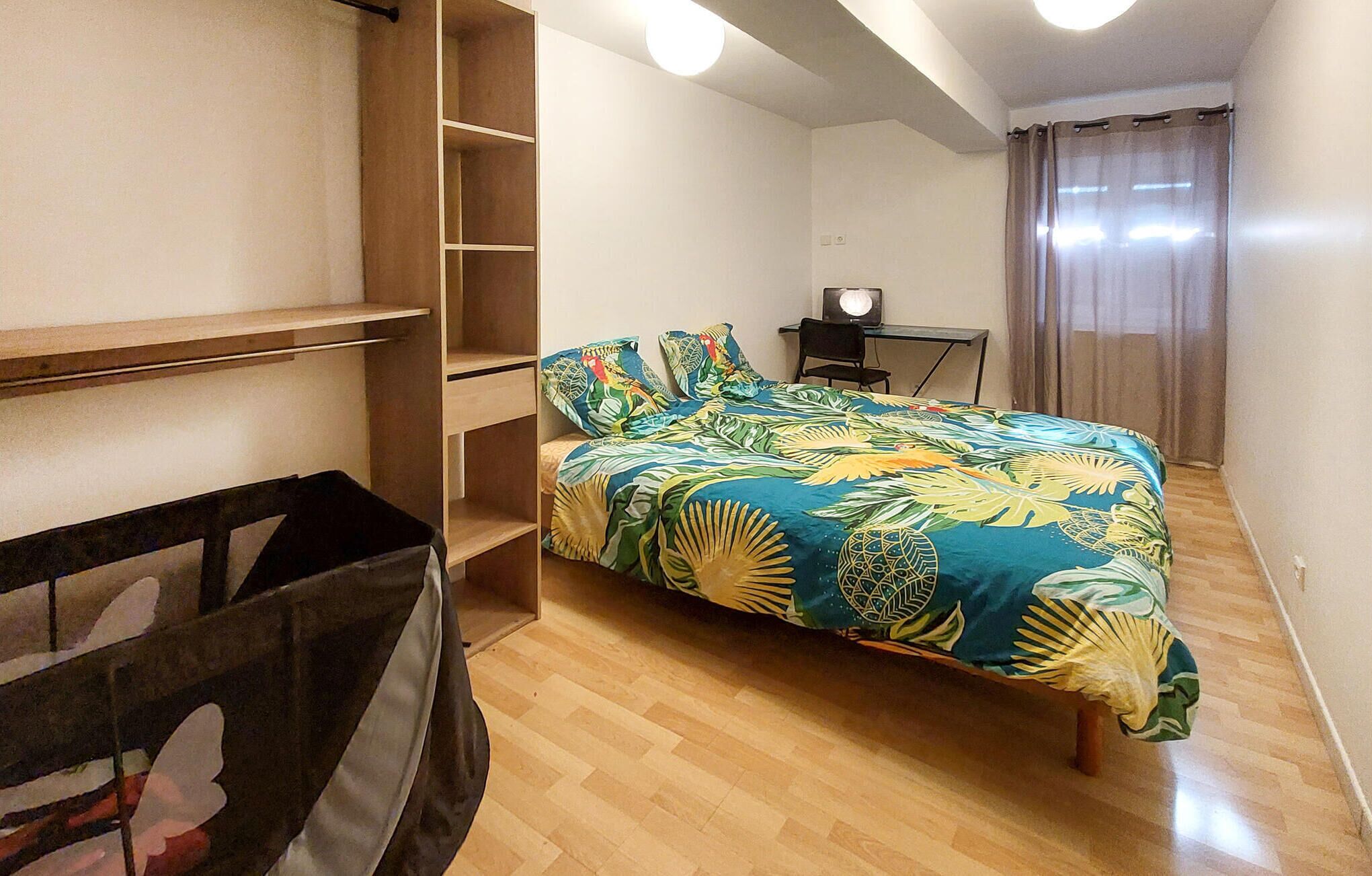 Ein Schlafzimmer mit einem Bett, einem Holzschrank, einem Schreibtisch und einem Stuhl.
