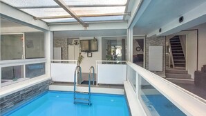 An indoor swimming pool with a glass ceiling, stone wall, and a visible staircase leading to an upper level. - Gorgeous home in Villars (Villars)