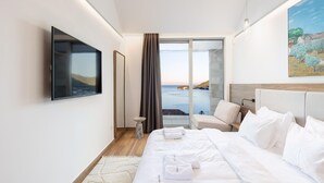Une chambre d’hôtel moderne dotée d’un grand lit, d’un téléviseur à écran plat, d’un tableau et offrant une vue sur la mer.