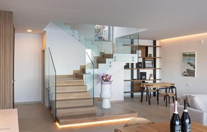 A modern interior with a staircase, a glass railing, a wooden table with bottles, and a bookshelf. - Beach front home in Vis with sauna (Vis)