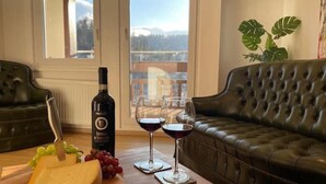Un tavolo da pranzo con una bottiglia di vino, due bicchieri, formaggio e grappoli d'uva.