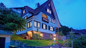 Una casa a due piani con un tetto spiovente, numerose finestre e un balcone.