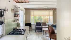 Cocina compacta con estufa a gas, comedor para dos personas y ventana con persianas.