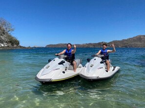 Two people on jet skis in clear water with a hilly landscape in the background. - Playa Potrero NEW 2 BR Condo Near to the Beach - Casa Blanca 7 (Tempate)