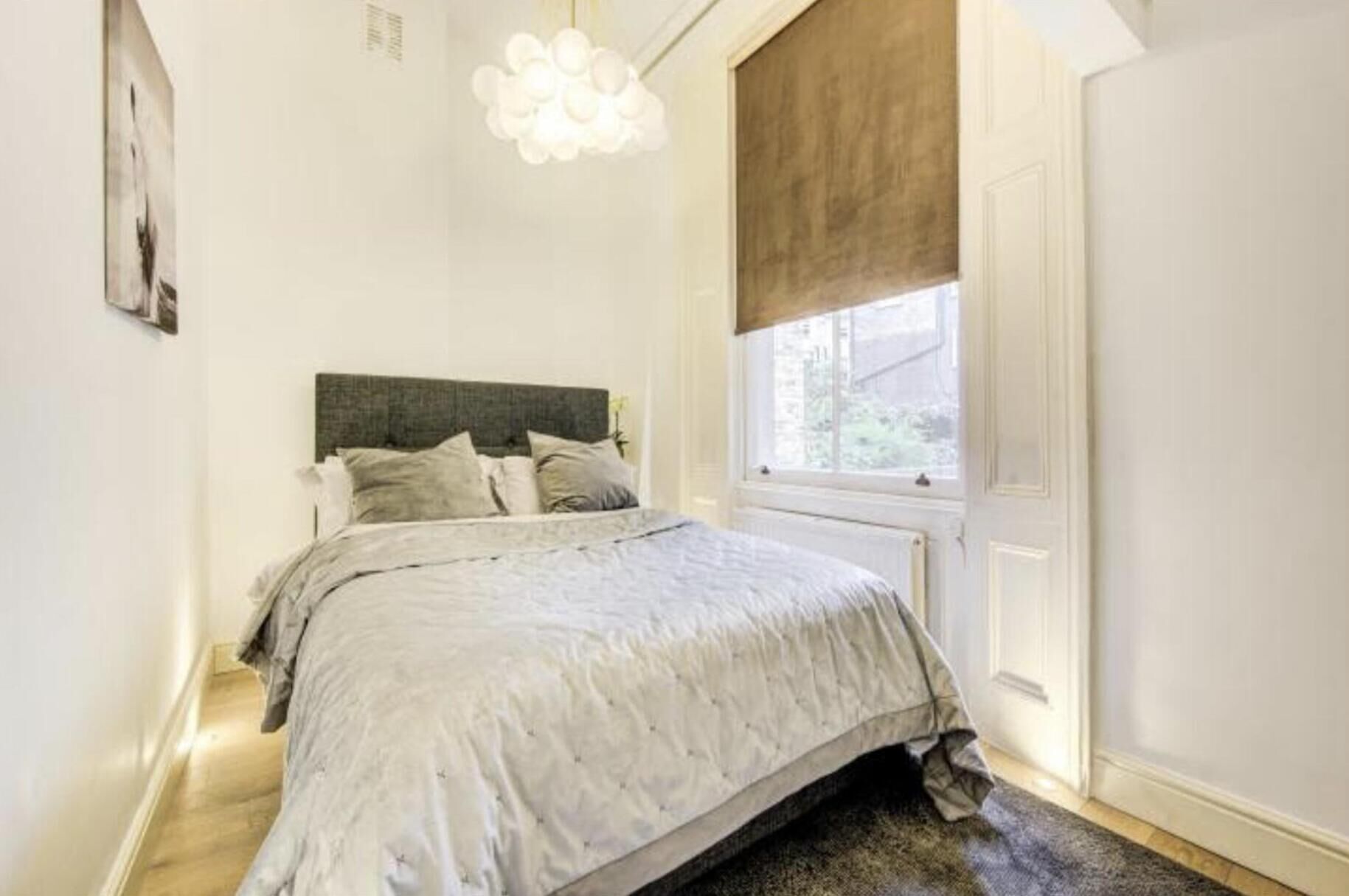 A bedroom with a bed, a window with a view, and a light fixture.